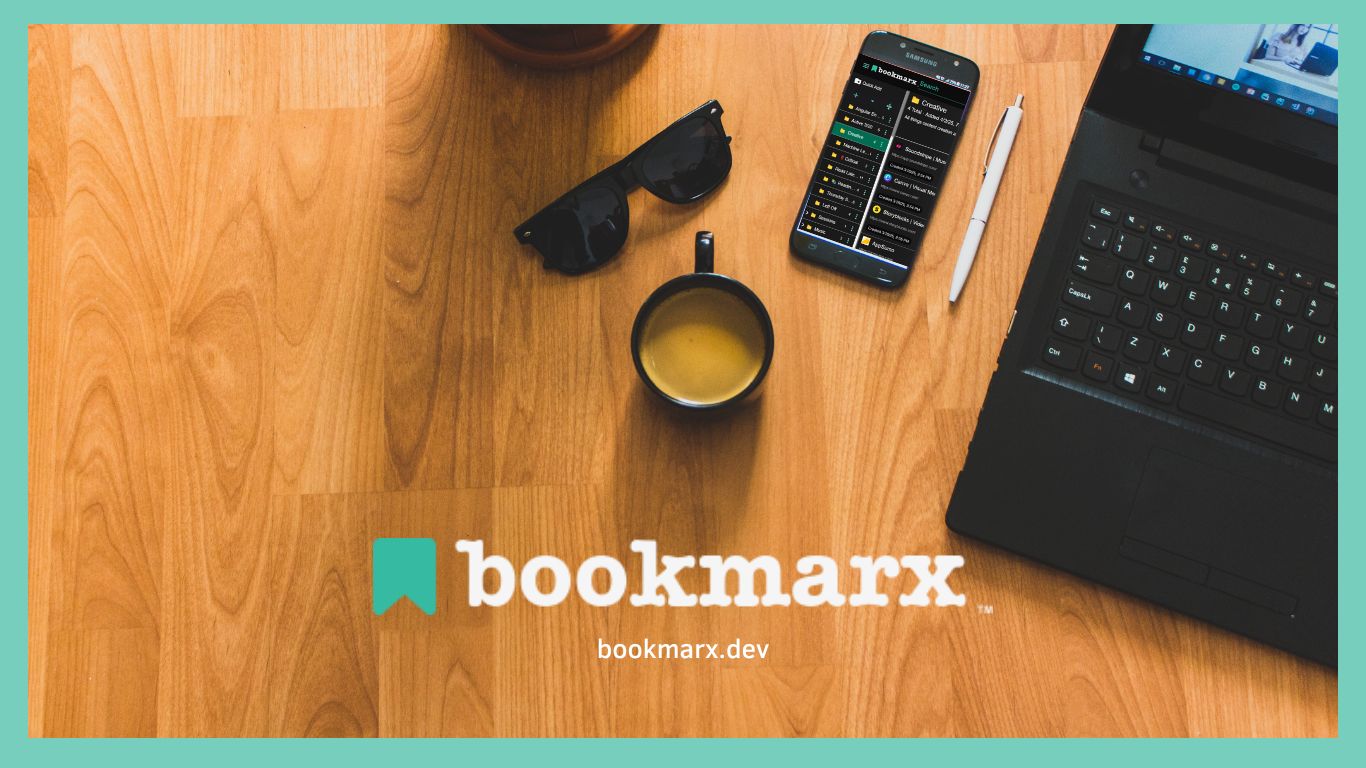 A wooden desk with a phone with bookmarx open on the screen and a laptop with a mug and small plant near it